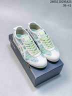 Pair of white Onitsuka Tiger sneakers with green and blue floral panels displayed on a shoe box.