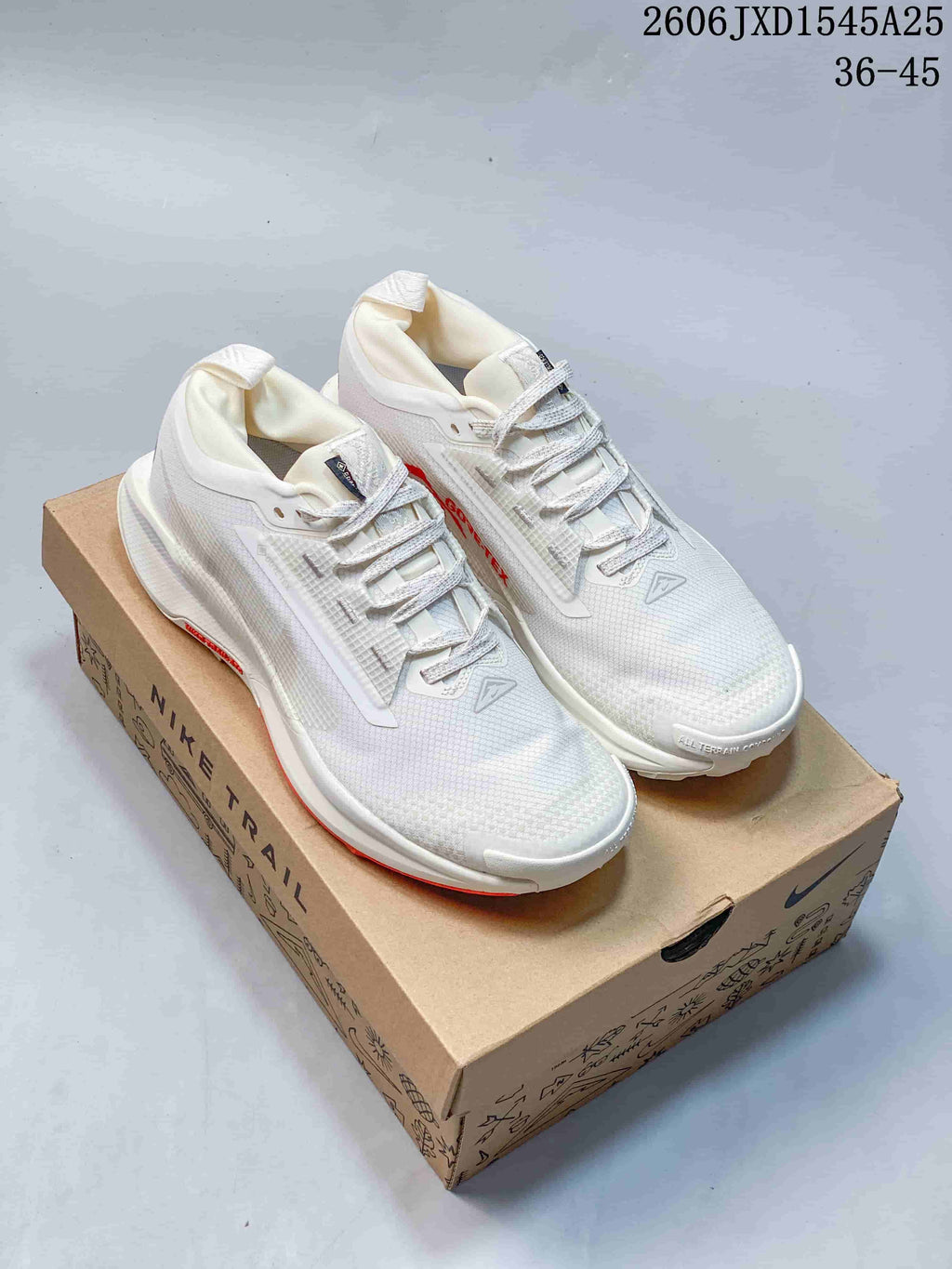Pair of white Nike Pegasus Trail shoes with red accents displayed on a shoe box