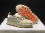 Angled view of the sneakers with one shoe lifted to reveal the outsole and its circular orange elements.