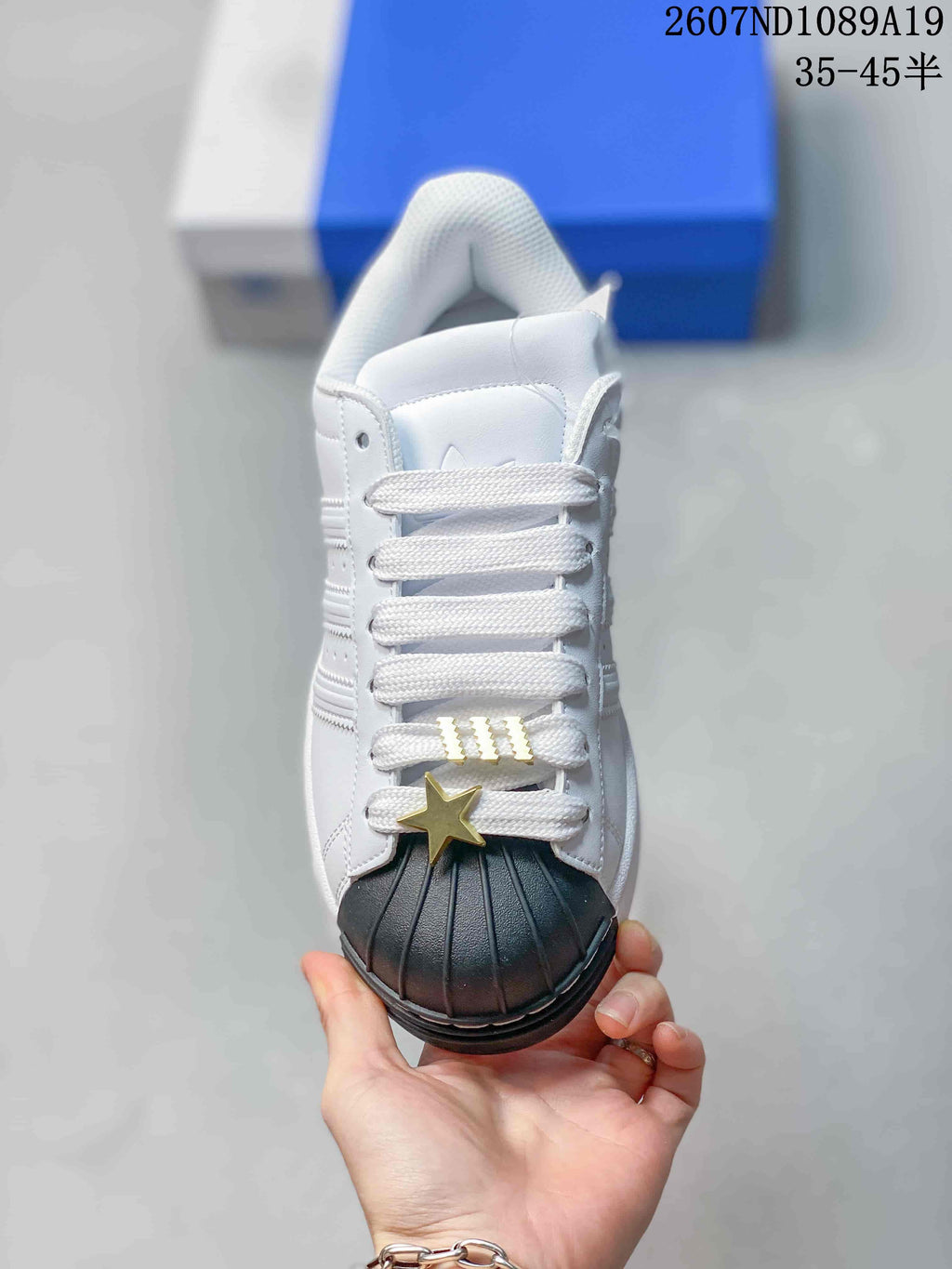 Top view showing white laces, gold-toned lace accessories, black shell toe, and perforated side panels.
