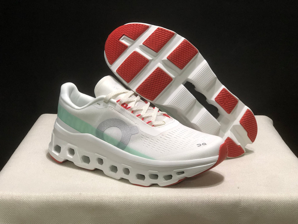 Angled product view showing one shoe's red-and-white outsole sections and the other shoe's white upper and sculpted midsole.