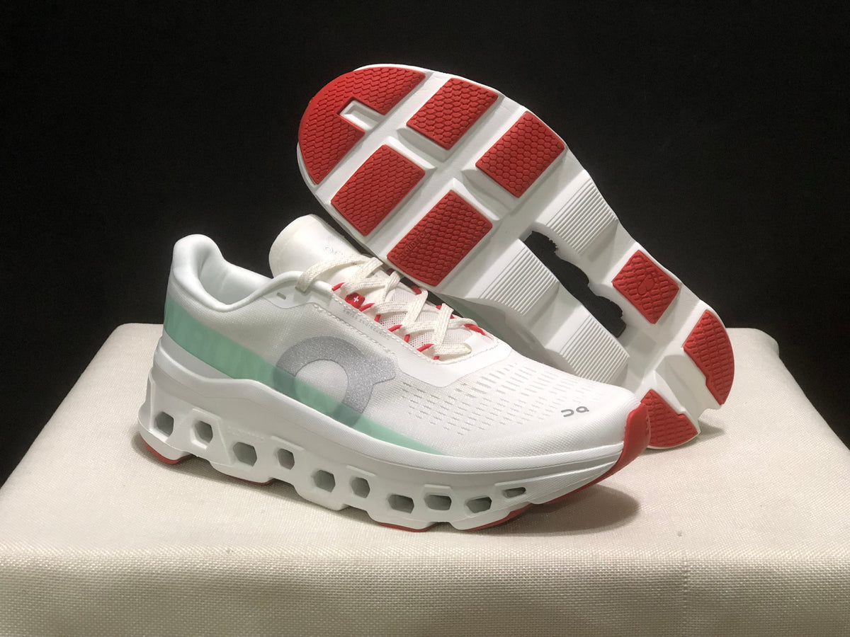 Angled product view showing one shoe's red-and-white outsole sections and the other shoe's white upper and sculpted midsole.