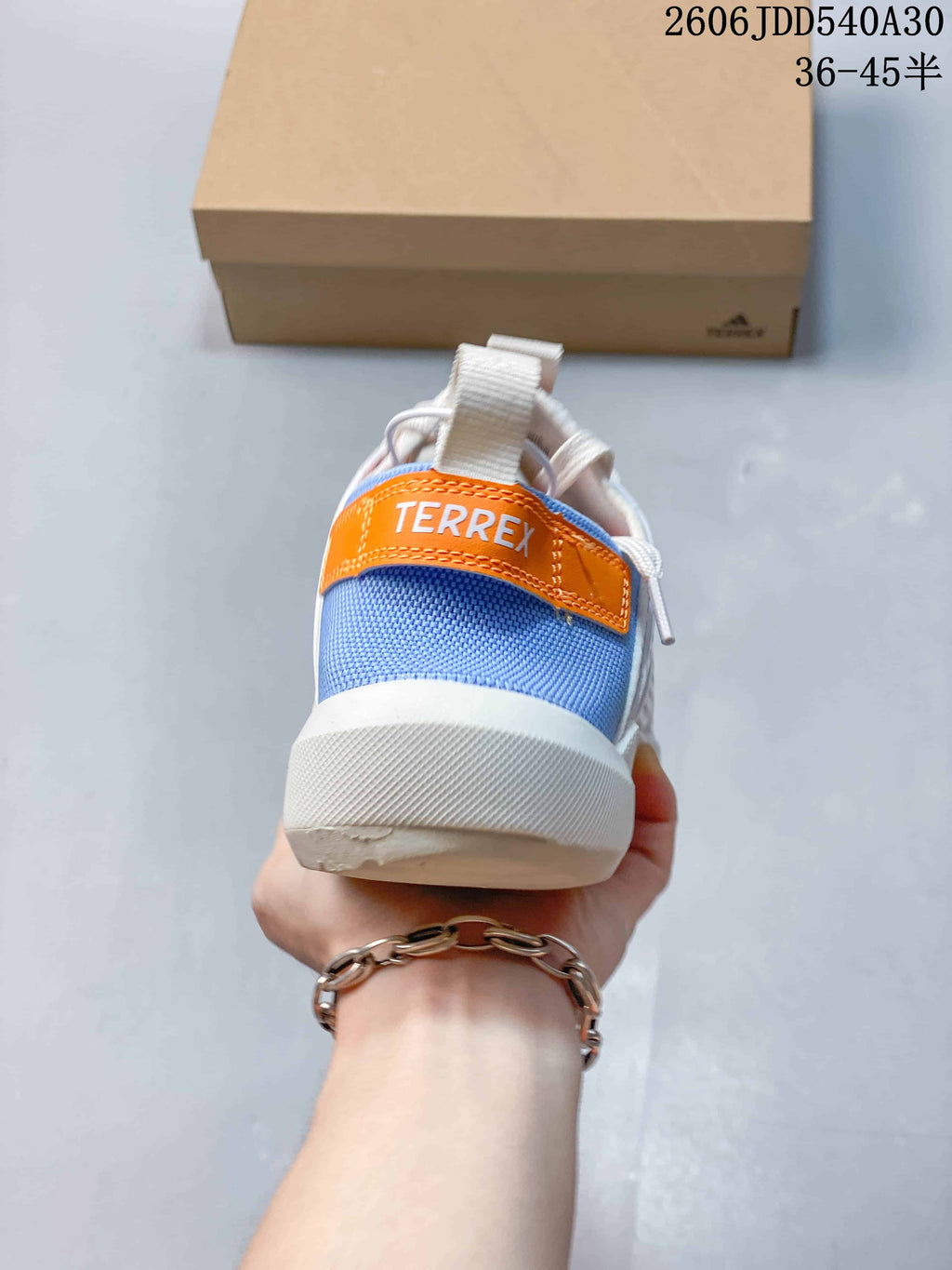 Rear view of the shoe with a blue heel panel and orange Terrex detail