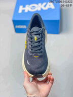 Top view of the sneaker showing the dark mesh-like upper, laces, tongue and yellow accent details.