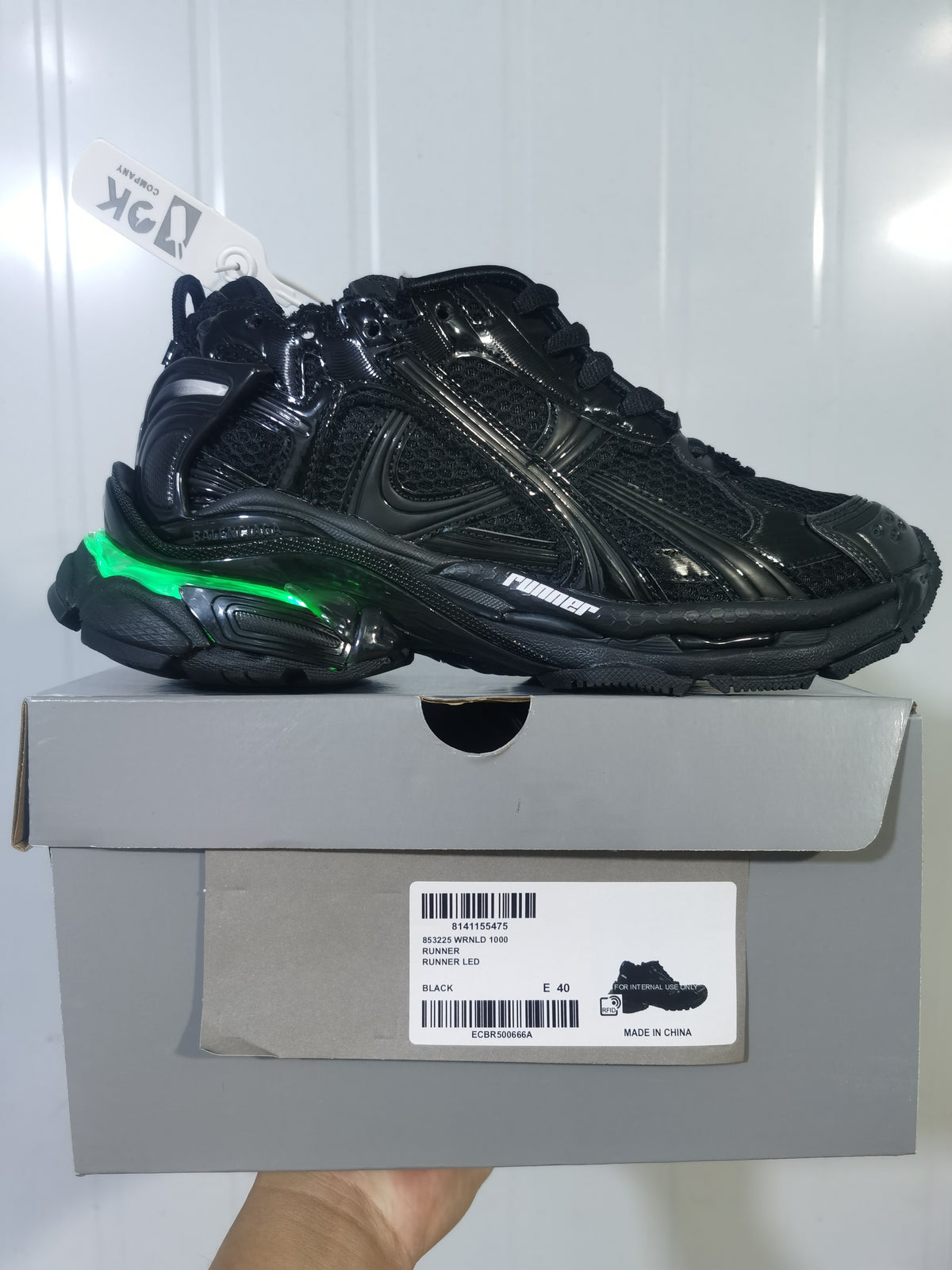 Side view of a black Puma Runner LED sneaker resting on its box, with a green illuminated heel accent and the box label visible.