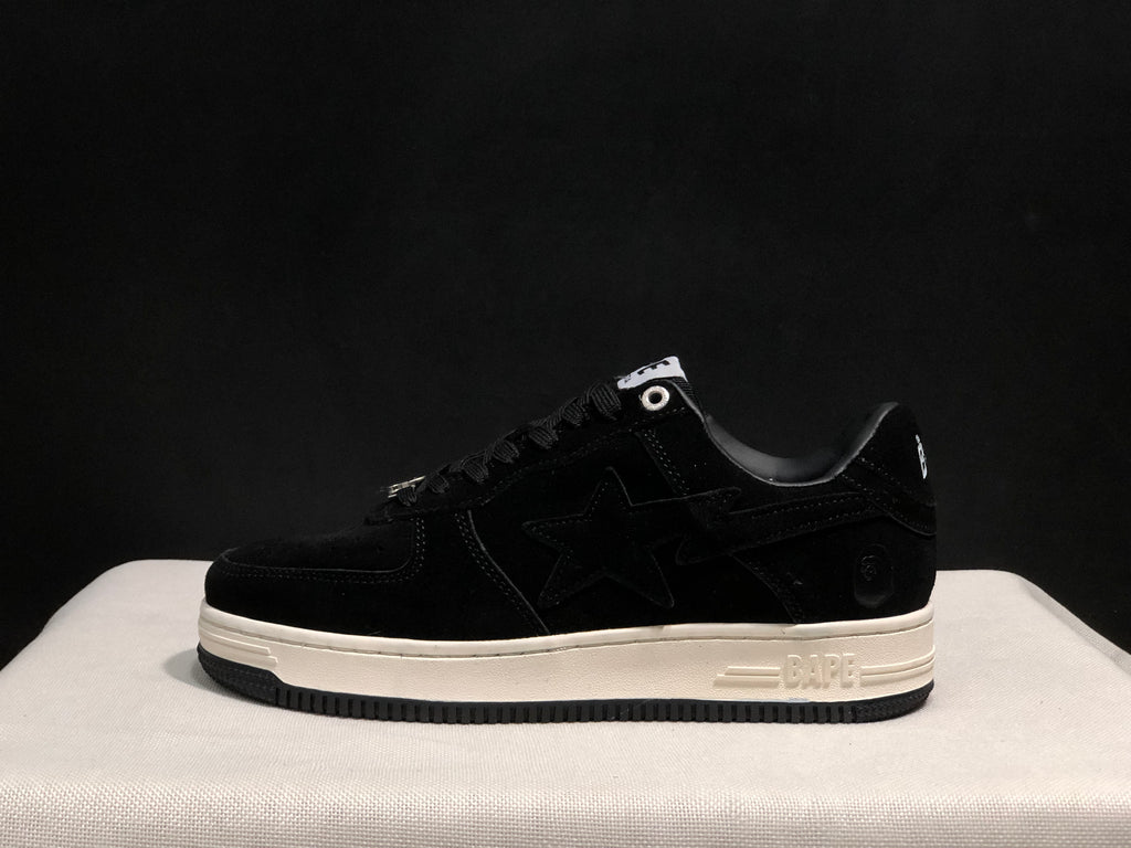 Side profile of a black low-top sneaker with a tonal star panel, white midsole and black outsole.
