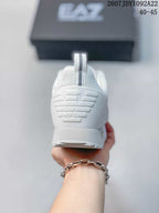 Rear view of a white EA7 sneaker showing the heel pull tab, embossed EA7 mark, and outsole edge; source overlay shows style code 2607JDY1092A22 and size range 40–45.