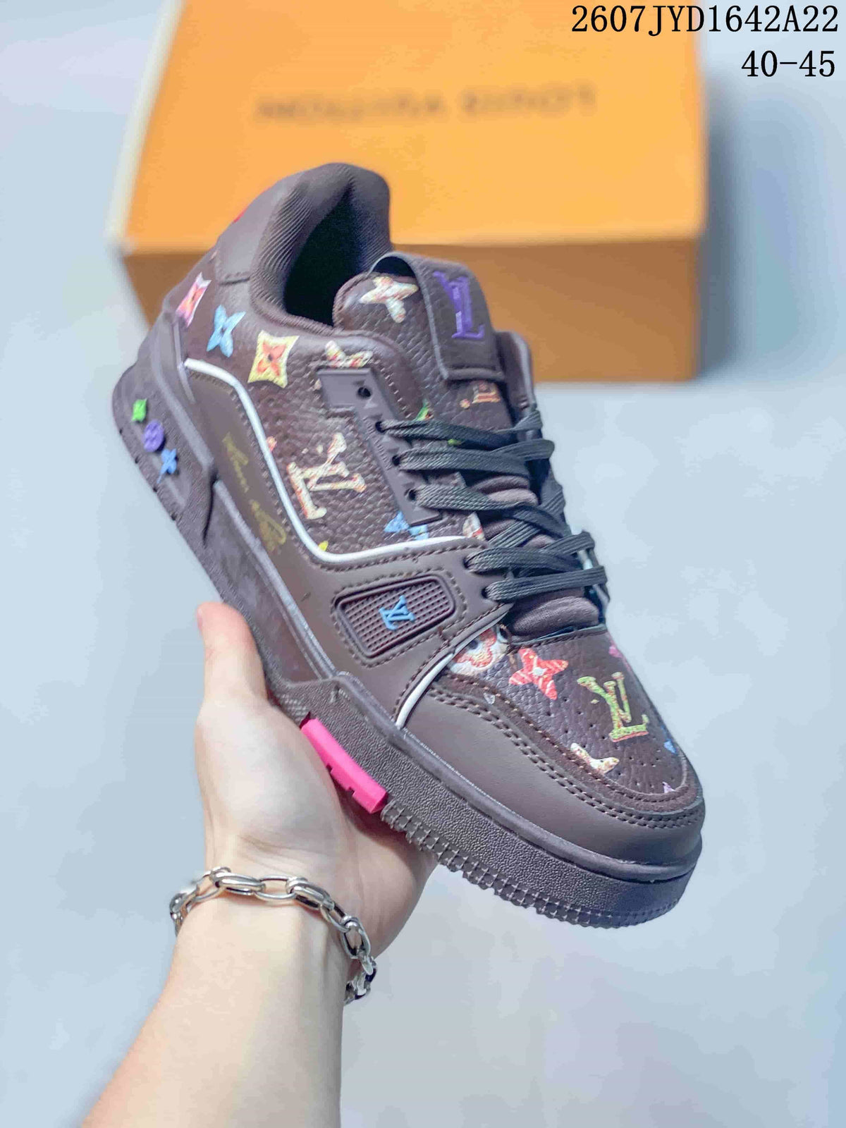 Angled side view of the dark brown Louis Vuitton Trainer sneaker with multicolor motifs and pink outsole accent; image text shows 2607 TYD1642A22 and 40–45.