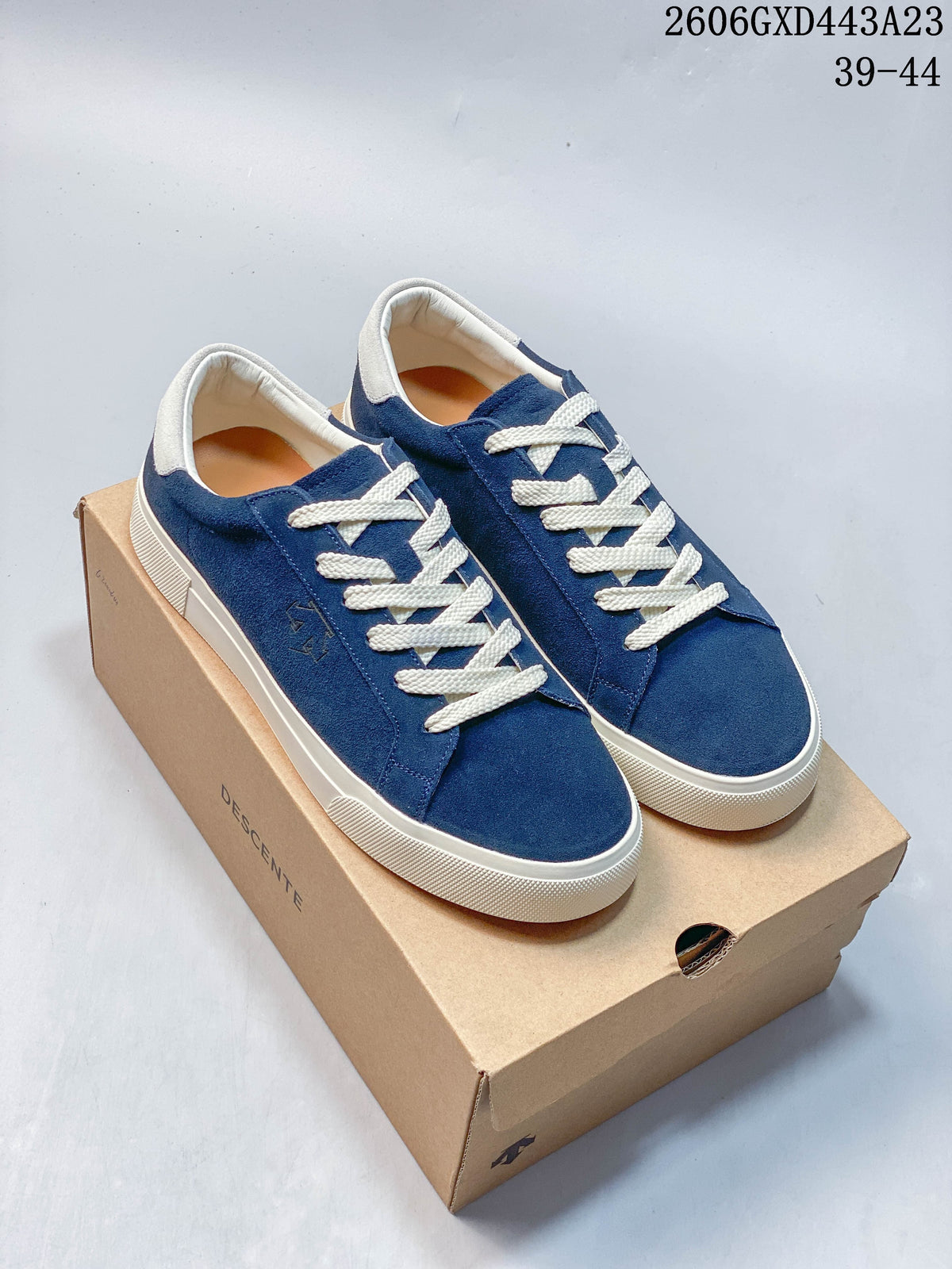 Blue DESCENTE Chron Chron sneakers with cream laces and trim, photographed on a box