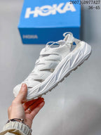 Side profile of the white HOKA Hopara OG sandal with open panels, toggle lacing and lugged sole.