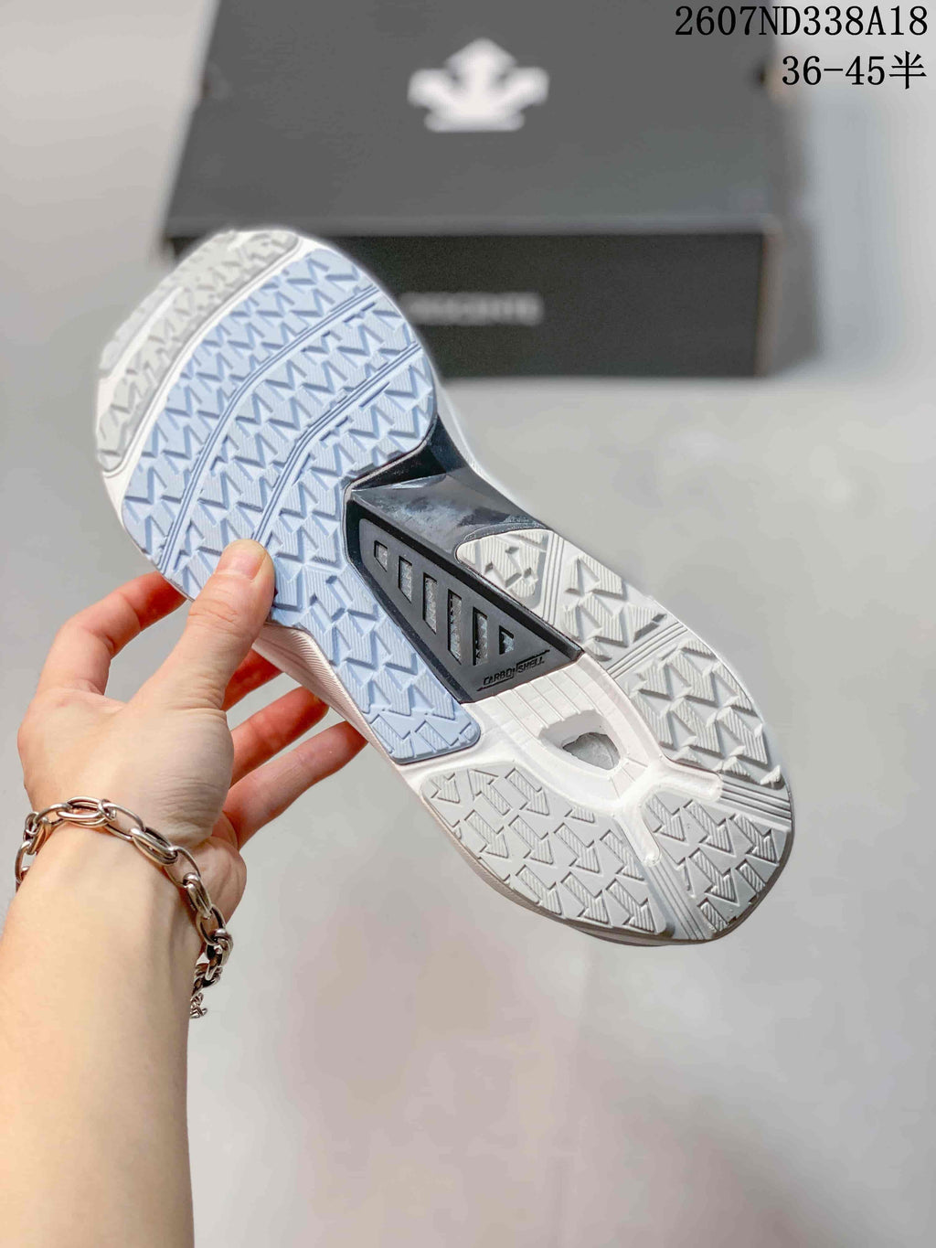 Underside view of the sneaker showing the patterned white outsole, blue traction section and central black support piece.