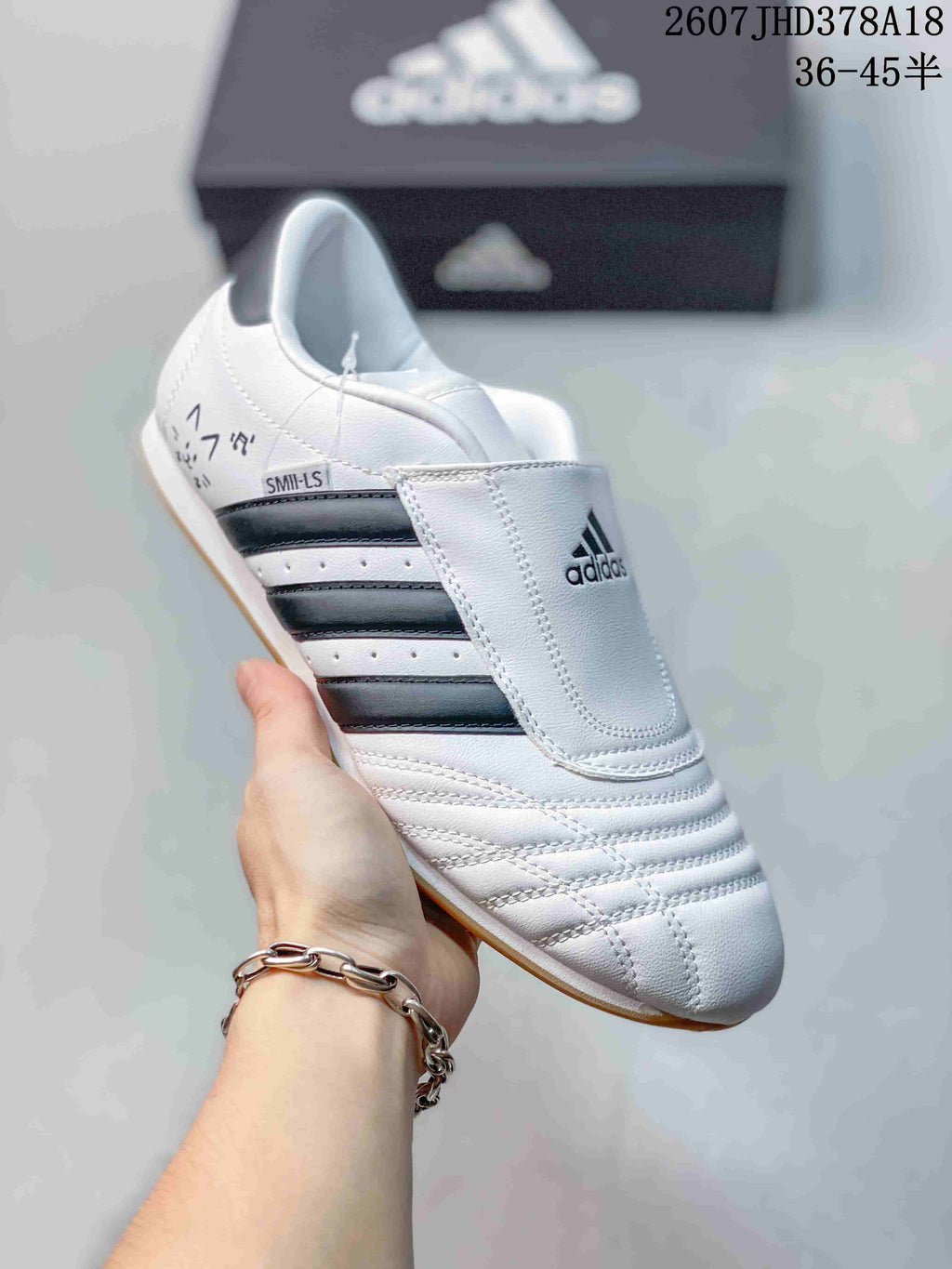 Close side view of a white adidas sneaker showing the tongue cover, dark stripes and SMIL-LS marking.