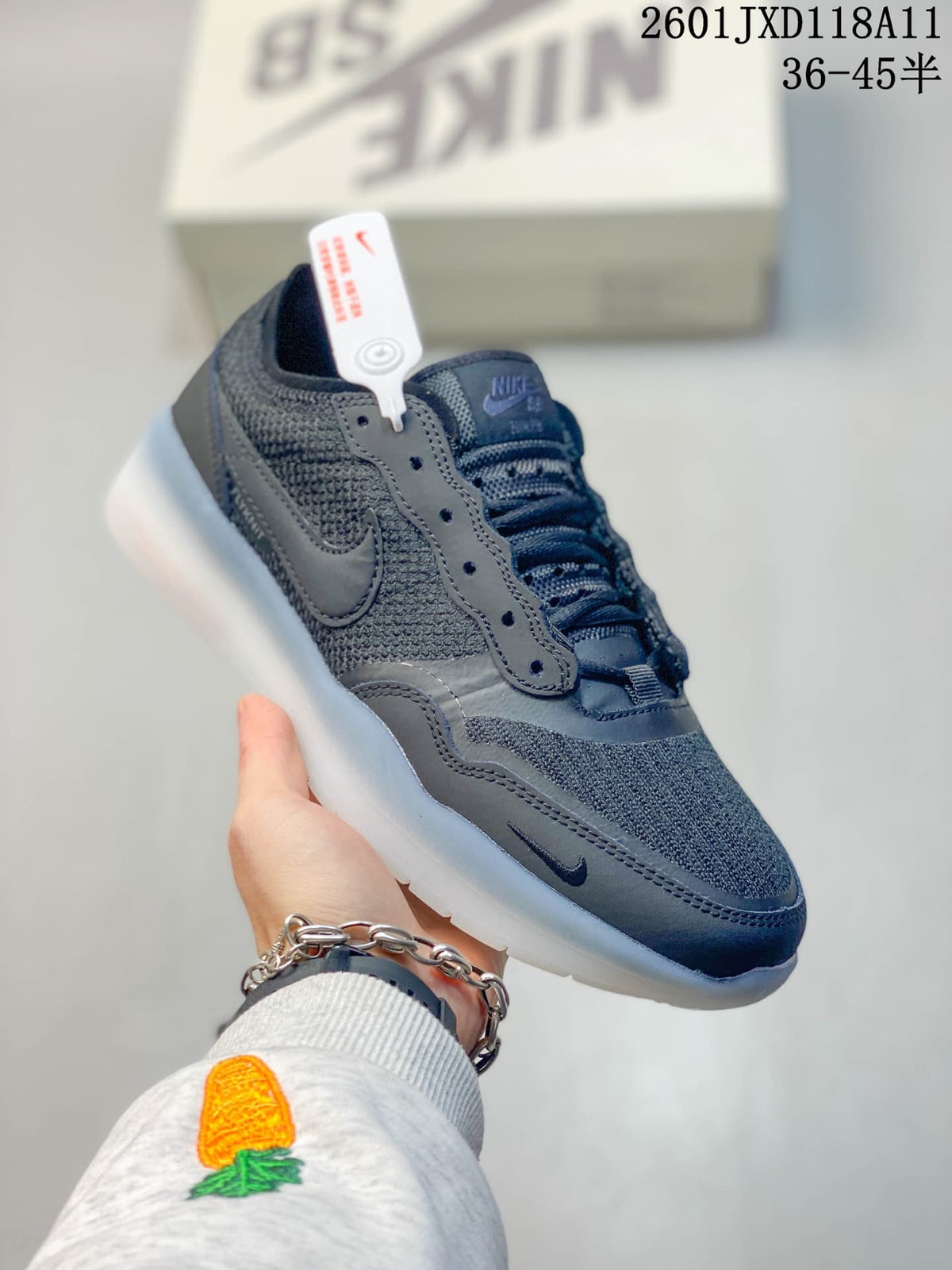 Angled side view of a dark gray Nike SB low-top shoe showing the layered upper, side Swoosh, and translucent outsole.