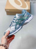 Side view of the ASICS Gel-Cumulus 16 sneaker showing layered mesh panels, blue overlays, silver details and green branding accents.