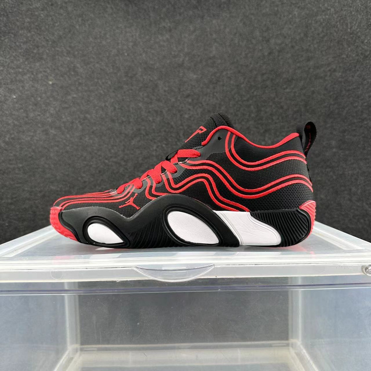 Side view of black Nike basketball sneakers with red wavy details, red laces, and white sole accents.