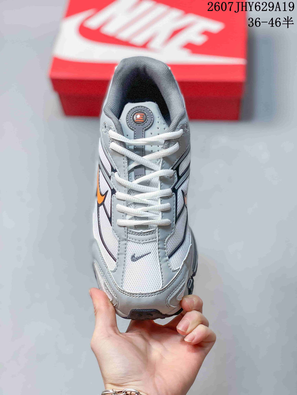 Top view of the grey and white lace-up sneaker with orange and black branding details.