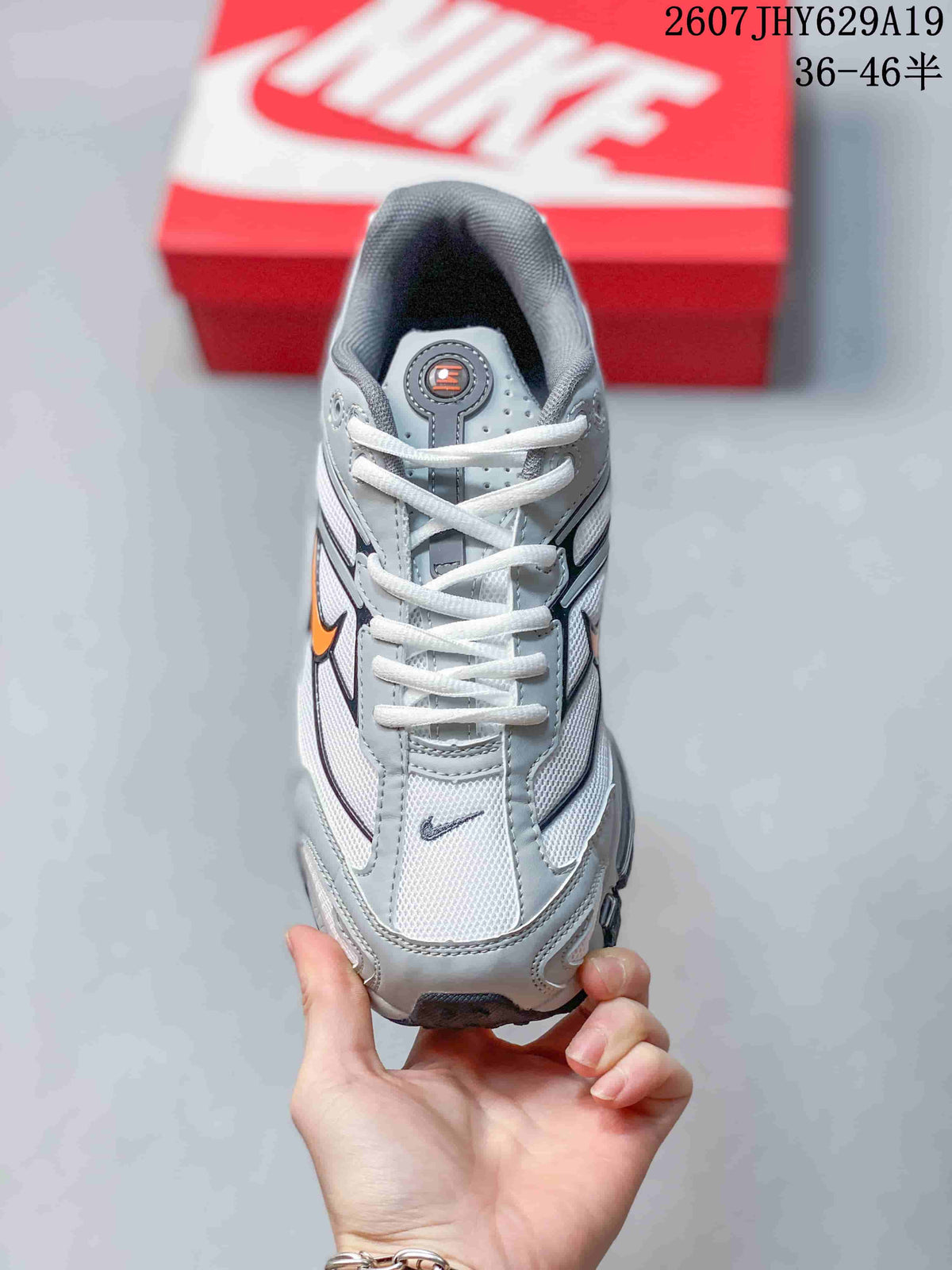 Top view of the grey and white lace-up sneaker with orange and black branding details.