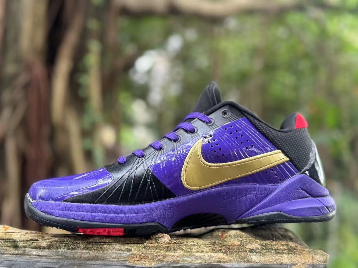 Side view of a purple and black Nike Kobe 5 shoe with a gold-colored logo and purple laces.