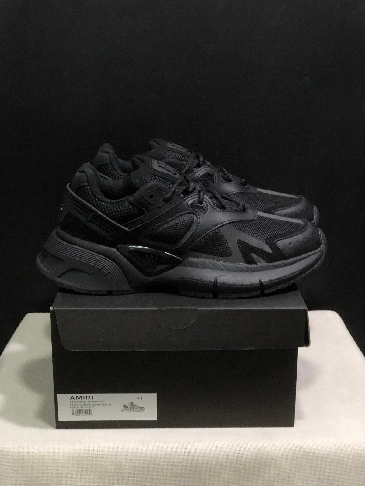 Side-front view of black AMIRI MA Runner sneakers with layered panels and chunky outsoles.