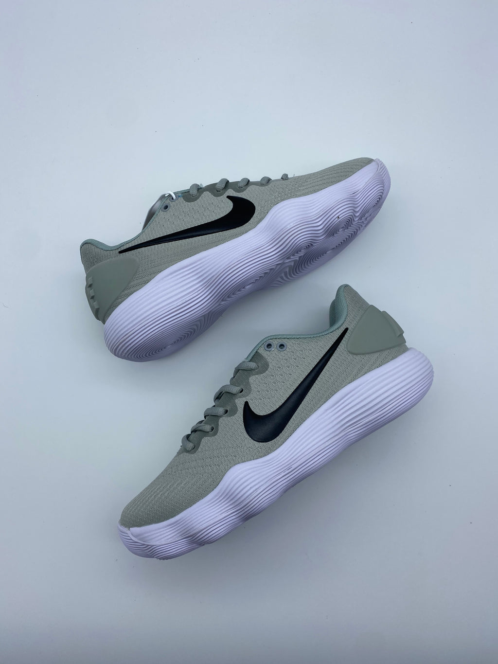 Pair of grey Nike low-top sneakers with black Swoosh logos and white ridged soles