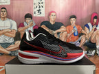 Side view of a black basketball shoe with patterned panels, red logo, and white midsole