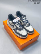 Pair of cream and charcoal Nike Air Force 1 Low-style custom sneakers on an orange box