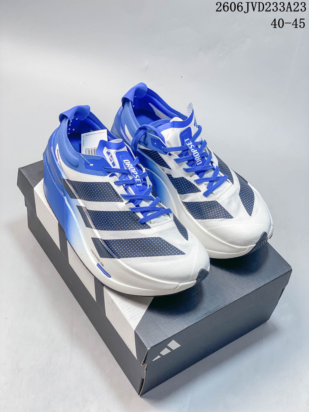 Pair of white and blue Adidas Adizero Prime X3 running shoes on a shoebox; image overlay shows EU size range 40–45.
