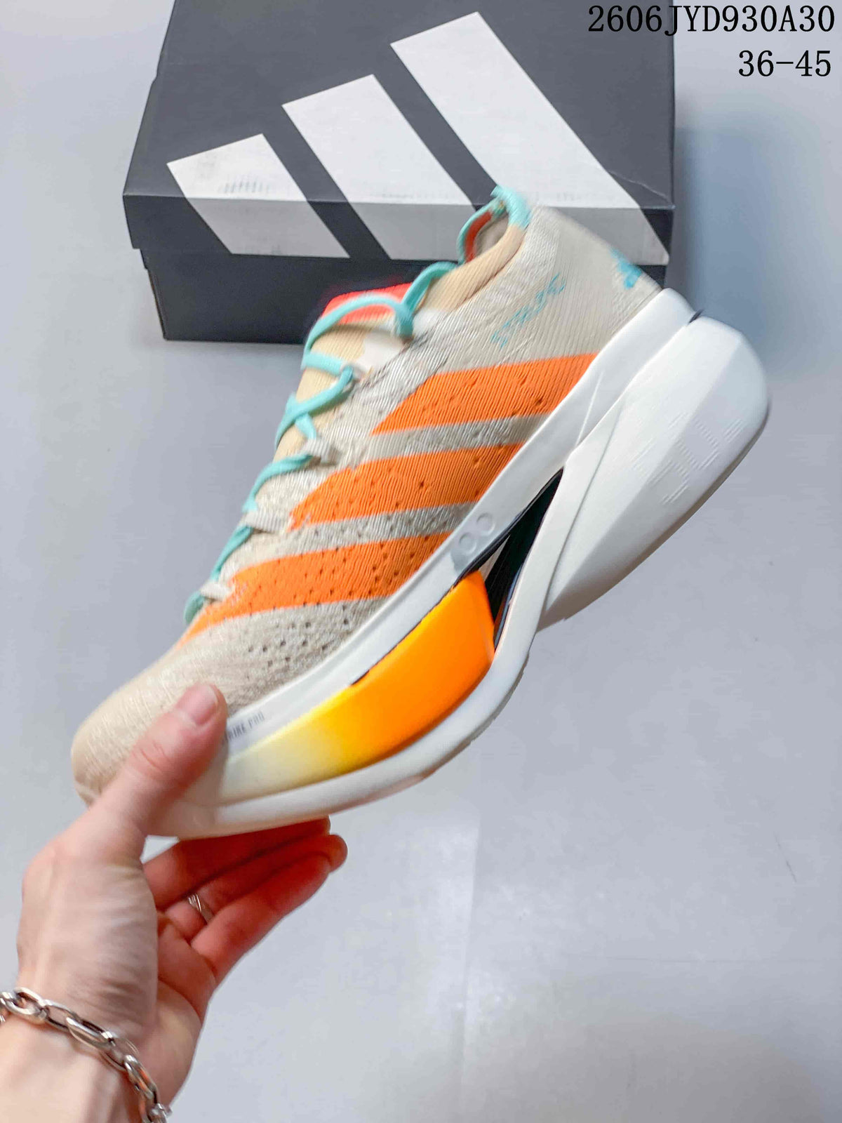 Side view of a beige running shoe with orange stripes, turquoise laces, and a sculpted sole