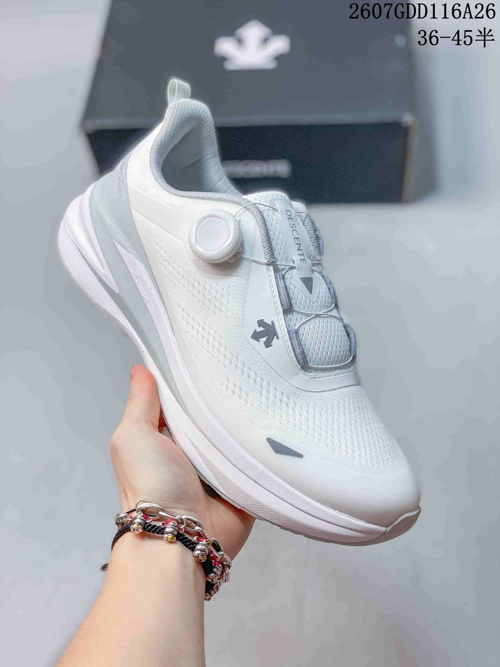 Angled side view of the white DESCENTE sneaker showing the dial closure, layered upper, and thick outsole.