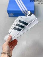Side profile of a white sneaker with black three-stripe detailing and a textured white sole.