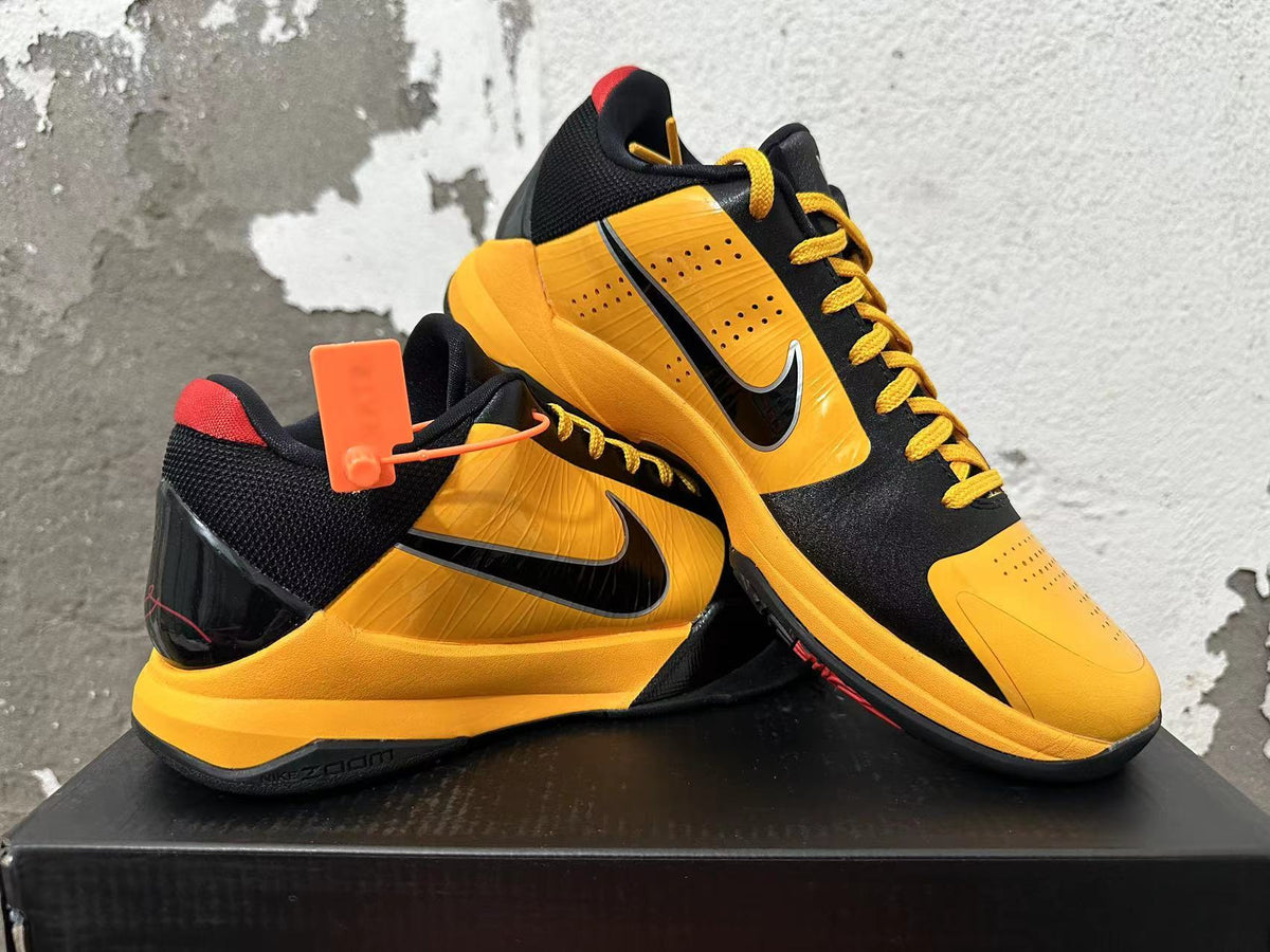 Pair of black and yellow Nike Kobe low-top basketball shoes shown at an angle