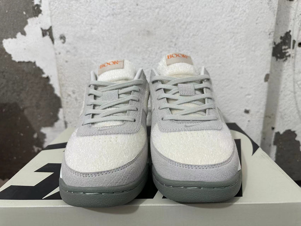 Front view of Nike Book 1 sneakers with gray laces and off-white textured toe panels.