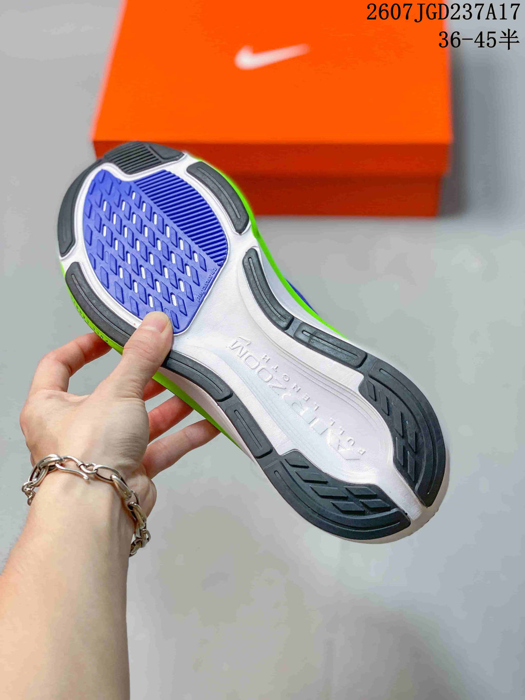 Underside view of a Nike Air Zoom Pegasus 42 shoe showing the white, purple, black, and bright green outsole pattern.