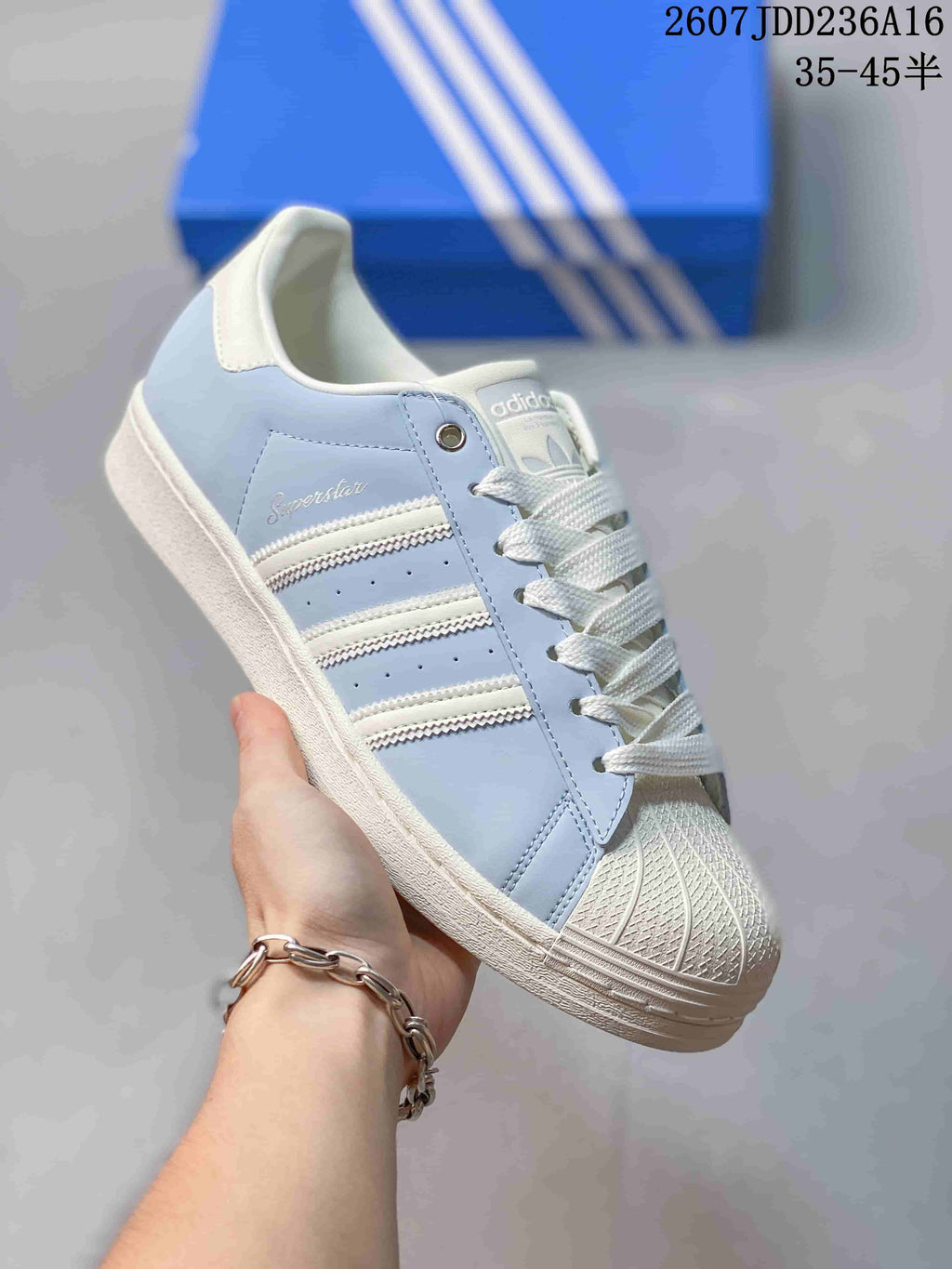 Angled side view showing the Superstar branding, three side stripes, shell toe, and white midsole.