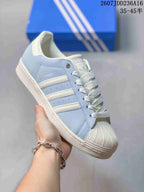Angled side view showing the Superstar branding, three side stripes, shell toe, and white midsole.