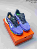 Pair of purple and blue Nike Air Zoom Pegasus 42 running shoes displayed on an orange shoebox, showing black laces, white Swoosh branding, and bright green accents.