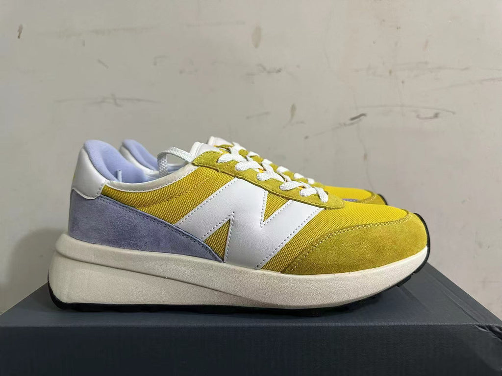 Side view of a yellow New Balance U370 sneaker with a white N logo and lavender heel panel