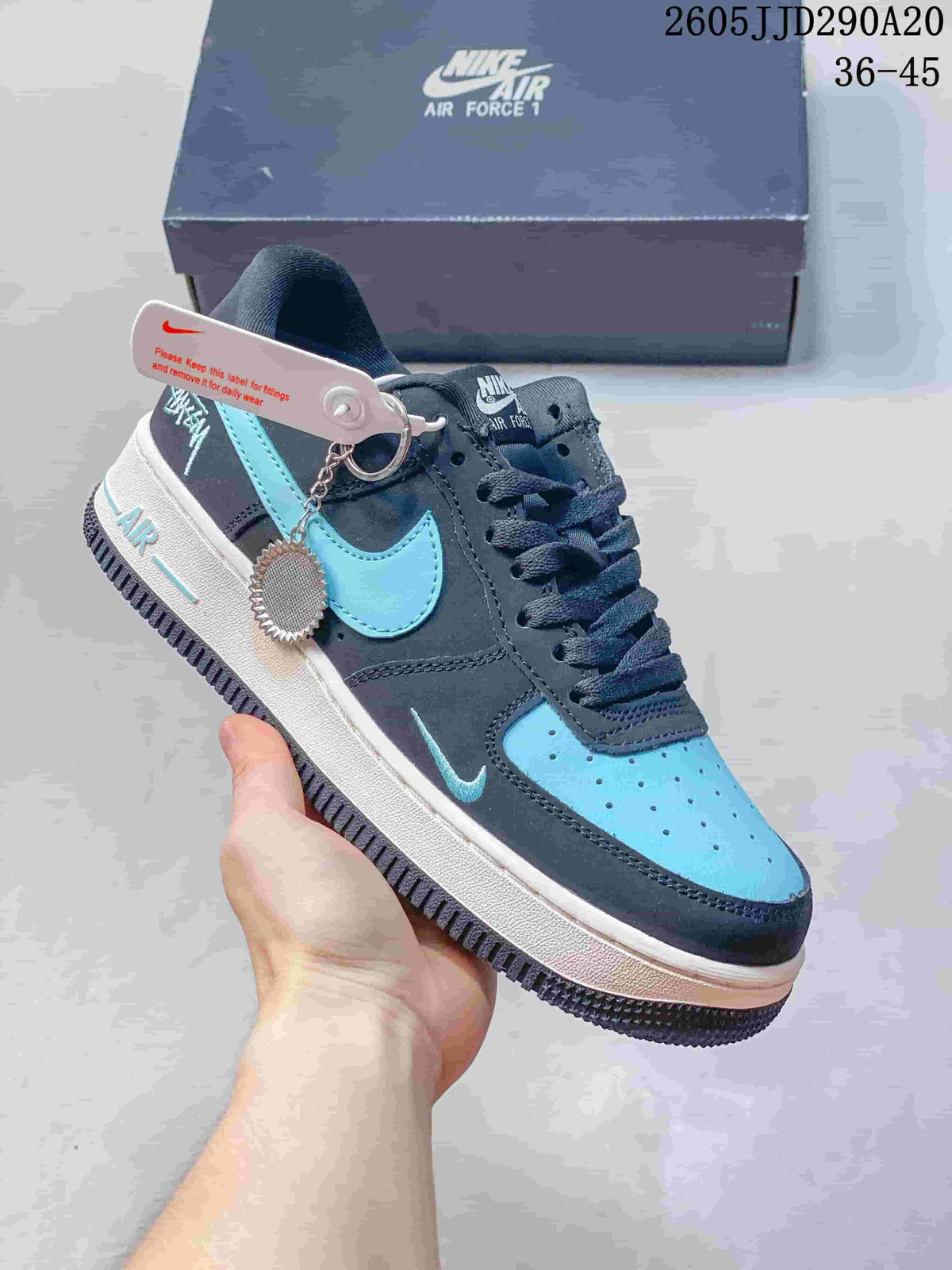 Dark navy and turquoise low-top sneaker with a layered Swoosh and charm detail