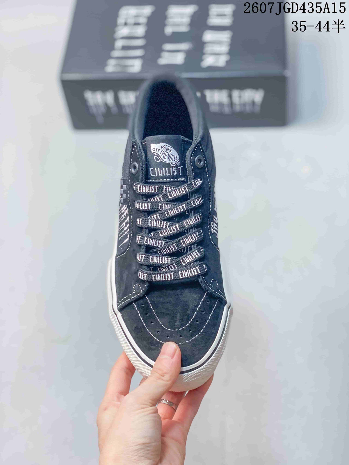 Top view of a black Vans sneaker with patterned laces, tongue branding and white stitching.