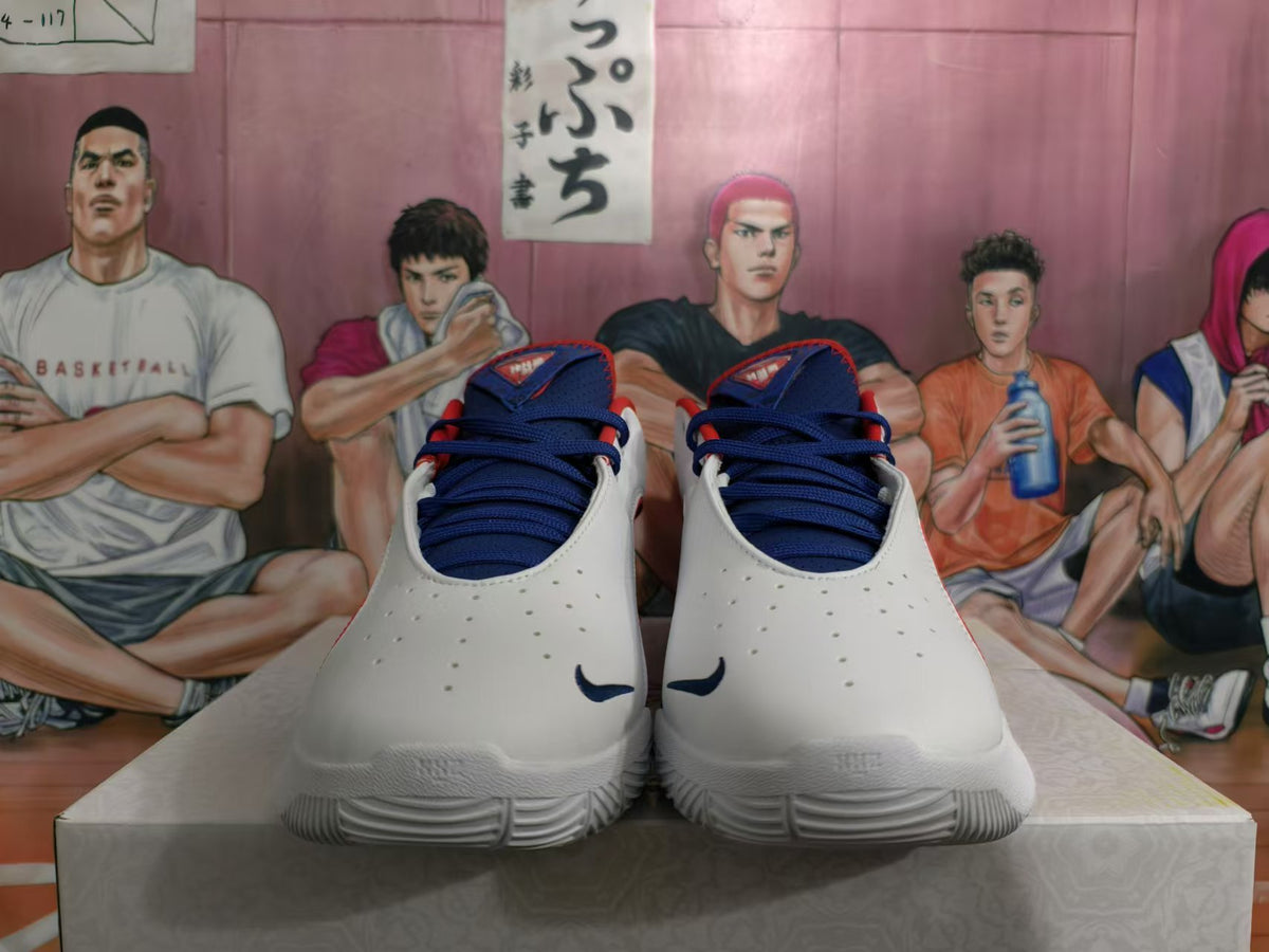 Front view of white Nike basketball shoes with navy laces and red collar accents.