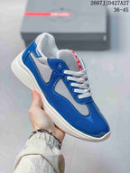 Angled side view of the blue and white Prada low-top sneaker with glossy overlays and a white sole.