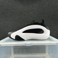 Side view of a white and black low-top sneaker with a sculpted white panel and black accents