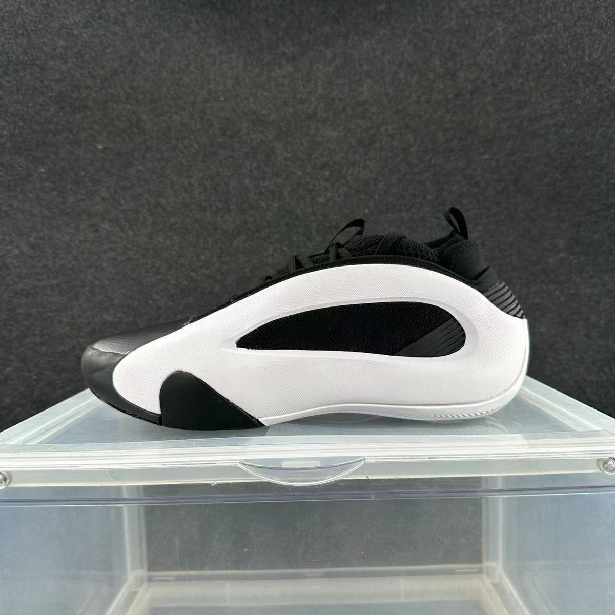 Side view of a white and black low-top sneaker with a sculpted white panel and black accents
