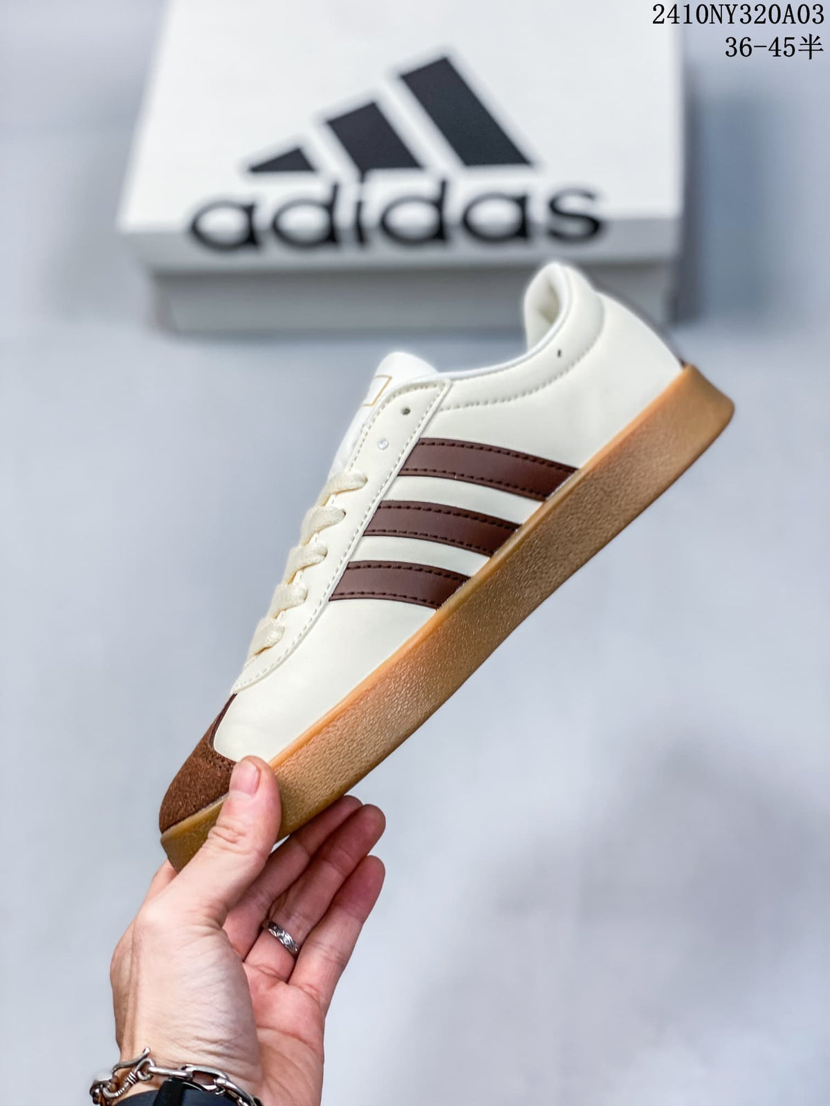 Side profile showing the white upper, brown three-stripe design, brown toe panel, and gum-colored sole.
