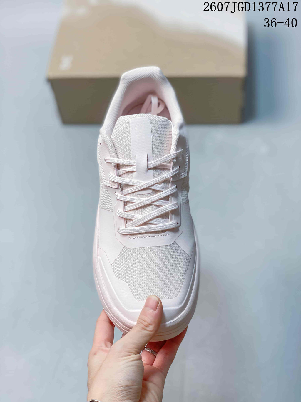 Top view of the sneaker showing the lace-up front, padded tongue, textured toe panel, and white and pale pink colorway.