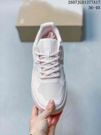 Top view of the sneaker showing the lace-up front, padded tongue, textured toe panel, and white and pale pink colorway.