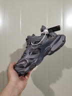 Dark grey Balenciaga open-panel sneaker shown from a side angle in hand.