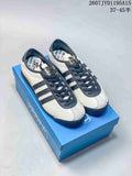 Pair of off-white and navy adidas x C.P. Company sneakers displayed on a blue shoebox.
