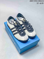 Pair of off-white and navy adidas x C.P. Company sneakers displayed on a blue shoebox.