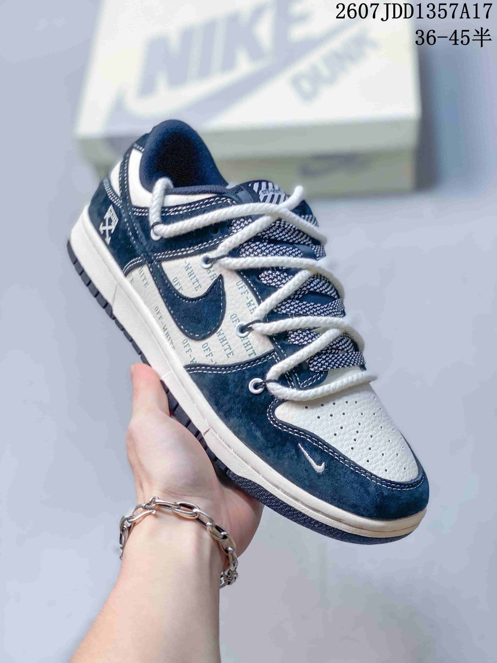 Angled side view of the navy and white sneaker showing the low-top shape, side branding, and layered laces.